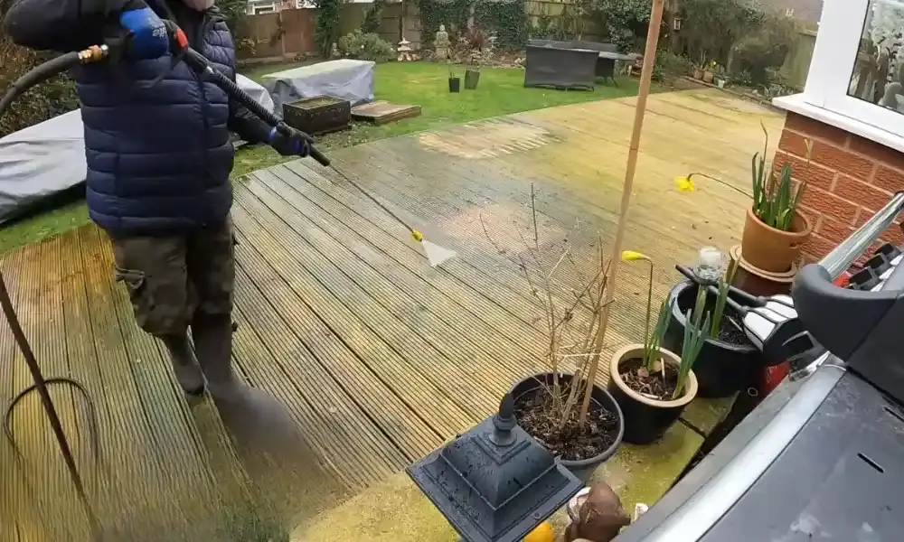 Professional cleaning a mossy wooden deck with pressure-washing equipment